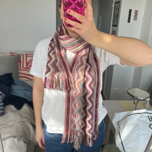 Flerfärgad halsduk från Missoni - Säljer en snygg och färgglad halsduk från Missoni med ett vågigt mönster i olika färger som rosa, blå, beige och röd. Halsduken är tillverkad i Italien och består av 90% ull och polyester😍😍