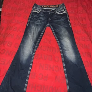 Rock revival jeans - Snygga mörkblå jeans från Rock Revival. Jeansen har en bootcut-stil och kontrasterande vita sömmar som ger en cool look. Säljer då de är för stora, skriv för frågor💗💕