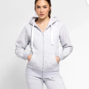 Russemerch zip hoodie - Säljer en stilren grå zip hoodie från russemerch med dragkedja och justerbar huva. Tröjan har långa ärmar och ribbade muddar vid ärmslut och nederkant. Säljer på grund av att den är för liten, knappt använd 💓