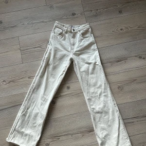 vita byxor från Zara - Snygga beige byxor från Zara i storlek EUR 34. Byxorna har en rak passform med hög midja och är tillverkade i ett mjukt bomullsmaterial. De har klassiska femficksdetaljer och stängs med dragkedja och knapp framtill. Villig att gå ner i pris!