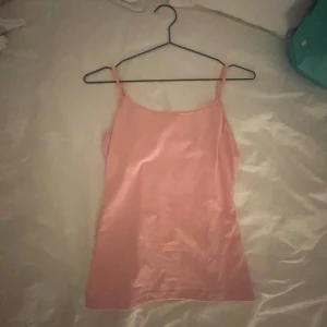 Rosa linnetopp  - Säljer en söt rosa linnetopp i mjukt och stretchigt material. Perfekt för varma dagar eller som ett lager under en tröja. Linnet har smala axelband och en enkel design som gör det lätt att matcha med andra plagg.