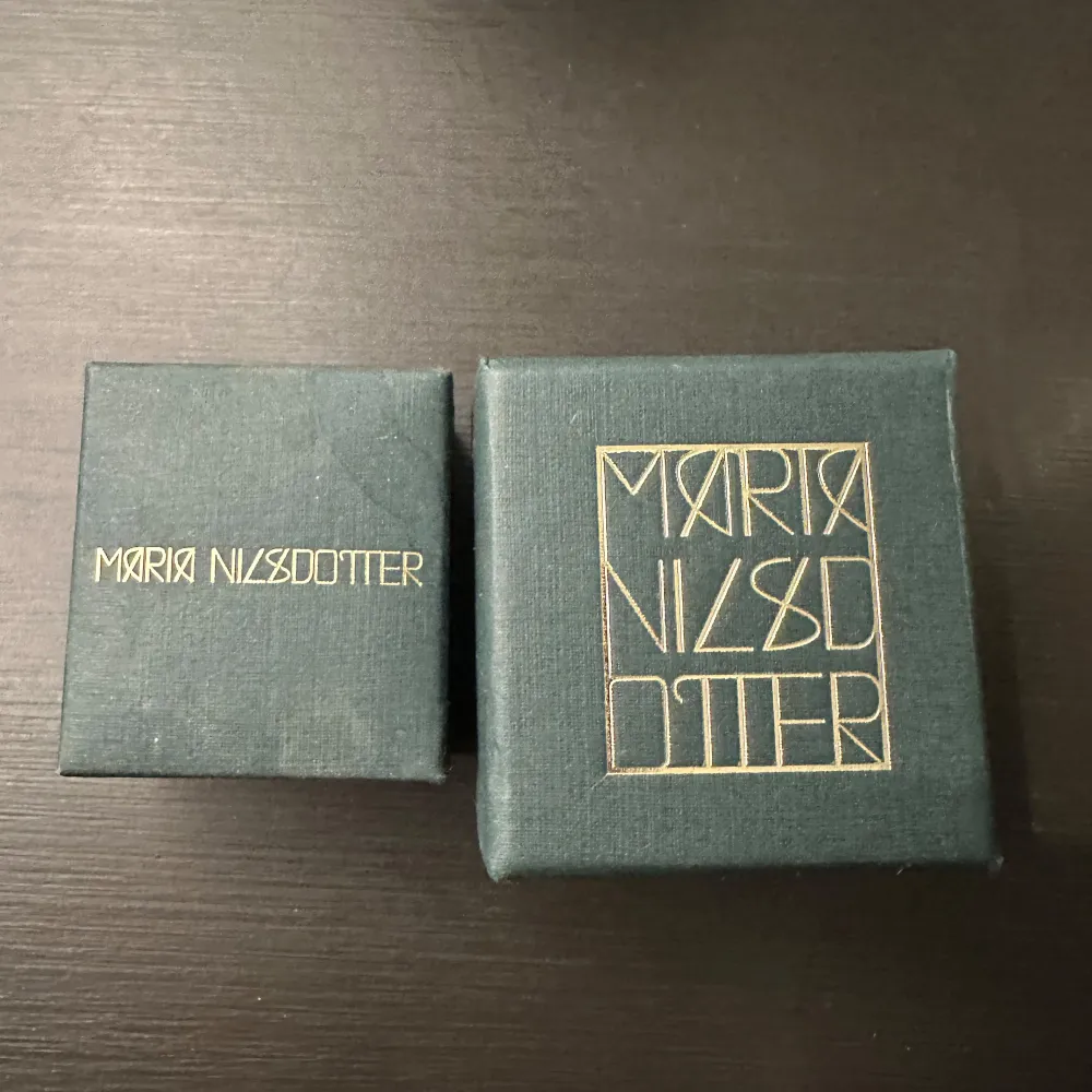 Säljer ett halsband från Maria Nilsdotter med en rund berlock. Ena sidan har texten 'Walk any way you want' och den andra sidan har ett motiv av fotavtryck. Halsbandet är i guldpläterat silver och kedjan är 45 cm lång. Knappt använd så i ny skick. . Asusteet.