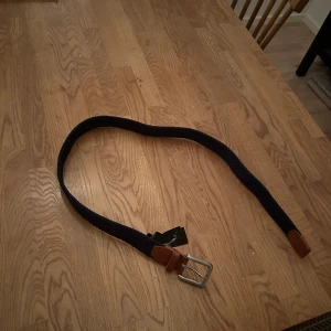 Blått bälte från Jack & Jones - Snyggt blått bälte från Jack & Jones med bruna läderdetaljer och silverfärgat spänne. 