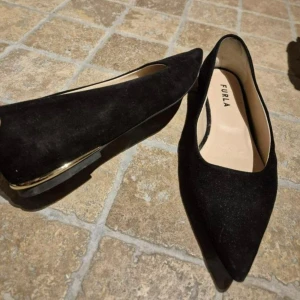 Svarta mocka pumps från Furla - Eleganta svarta ballerina i mocka från Furla med spetsig tå och en subtil klack. Perfekta för en stilren look.