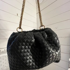 Svart flätad axelväska med kedja - Så snygg handväska från Gina!! Aldrig använd, ryms mer saker i den än vad man tror, har inga mått eller fler bilder