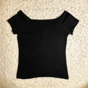 Svart offshoulder topp - Snygg svart offshoulder topp med korta ärmar. Perfekt för en stilren look. Passar bra till både jeans och kjol.
