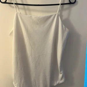 Vit linnetopp från Bik Bok - Säljer en stilren vit linnetopp från Bik Bok. Toppen har smala axelband och en enkel design som passar perfekt till sommaren. Perfekt för att matcha med jeans eller kjol för en avslappnad look.