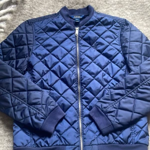 Mörka blå vår/höst jacka från Polo Ralph Lauren - Säljer en snygg blå quiltad bomberjacka från Polo Ralph Lauren. Jättebra skick, inga hål eller så. Skulle säga att den passar 13-16 åringar, alltså L på barn.
