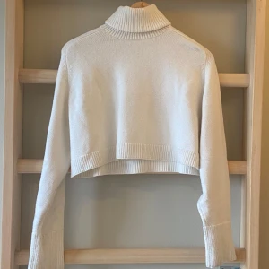 Vit croppad polotröja från Zara - Snygg vit croppad polotröja med långa ärmar och ribbade detaljer vid ärmslut och nederkant, från Zara. Jag tycker om den väldigt mycket men måste göra plats i garderoben.  Den har inga synliga defekter.💞🎀