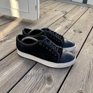 Lanvins uk 7 passar 41/42 - Snygga marinblå sneakers från Lanvin med en stilren design. Skorna har en kombination av mocka och skinn med en vit sula. Perfekta för en casual look med snörning framtill. Bra skick inget og tillkommer kvitto finns ej, priset går att diskutera vid snabb affär.