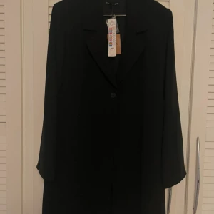 Svart kappa från Kaffe - Elegant svart kappa från Kaffe med klassisk design. Den har långa ärmar och stängs med knappar framtill. Perfekt för en stilren look🥰 storlek 42! Tunnare material så perfekt till våren🌸nypris 600kr, köpt på Sellpy men aldrig använd! Alla lappar kvar☺️