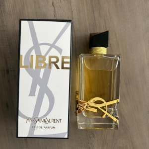 Yves Saint Laurent Libre EdP 90ml - YSL Libre Eau de Parfum i en lyxig, rektangulär glasflaska med guldiga detaljer och svart asymmetrisk kork. Doften är elegant och flaskan pryds av YSL-loggan i metall. Innehåller 90 ml och kommer i originalförpackning.