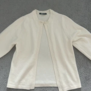 Vit kofta från Gina Tricot XS - Klassisk vit kofta från Gina Tricot i storlek XS. Den har rund halsringning, ribbade kanter och stängs med en knapp upptill. Långärmad och i mjukt stickat material, perfekt att slänga över en topp när det blir lite kyligt. Endast använd 1 gång!💕