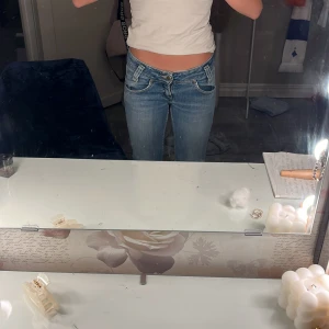 Blå low waist jeans Lee 25/31 - Snygga blå bootcut jeans med låg midja och klassiska fickor fram och bak. Jeansen har en lätt tvättad look och sitter tajt upptill med utsvängda ben. Materialet är bomull med lite stretch för extra komfort.