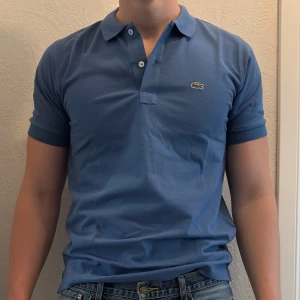 Blå Lacoste piké t-shirt - Vanlig ljusblå lacoste piké. Tröjan är helt ny. Säljer även ut andra saker från min gaderob så kolla gärna min sida och se om du hittar något du gillar!