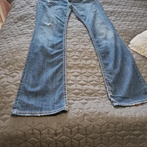 Blå bootcut jeans från MEK Denim - Snygga blå jeans från MEK Denim med bootcut passform. Jeansen har slitna detaljer, kontrastsömmar och coola bakfickor med knappar. Klassisk femficksmodell i mjukt denimtyg, perfekt för dig som gillar en avslappnad och trendig look.den är i väldigt fin skick