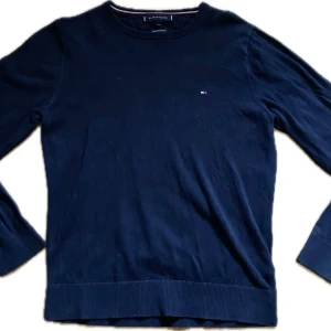 Mörkblå bomullströja Tommy Hilfiger XS - Snygg mörkblå tröja från Tommy Hilfiger i premium bomull. Klassisk rund halsringning, långärmad och med diskret logga broderad på bröstet. Perfekt basic-plagg med ribbade muddar och stilren look.