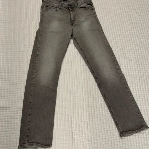 Replay grå jeans straight fit - Snygga grå jeans från Replay i rak modell med klassiska fem fickor och diskreta slitningar. Jeansen har normal passform och är tillverkade i mjukt denimtyg. Perfekta för dig som gillar en clean och stilren look. Passar för dig som är typ 160-165 är man kortare blir dom mer baggy