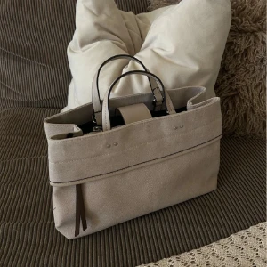 HELT NY Beige tote handväska från Parfois - Stilren tote handväska i beige canvas från Parfois. Väskan har dubbla handtag, minimalistisk design och detaljer i ljusbrunt. Perfekt storlek för att få plats med allt du behöver. Snygg accessoar som lyfter din look. OANVÄND MED ALL PLAST PÅ. 