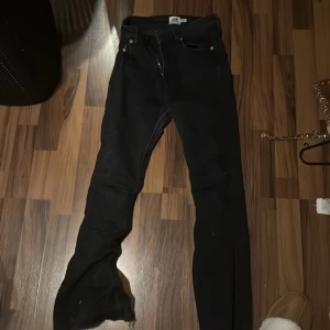 Svarta jeans från laget 157  - Svarta jeans från lager 157 med klassisk femficksdesign och raka ben. Jeansen har en enkel look med silverfärgade nitar och knapp, samt dragkedja i gylfen. Perfekt för dig som gillar en clean och tidlös stil.