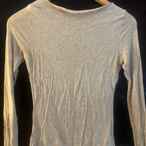 Ljusbeige långärmad topp Intimissimi - Supermjuk och tunn ljusbeige långärmad topp från Intimissimi, tillverkad i en mix av ull och kashmir. Enkel och stilren design med rund halsringning, perfekt att styla lager på lager eller som den är.