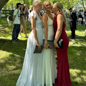 Vit klänning med spetsdetaljer - Säljer en vacker vit klänning med spetsdetaljer och knytband på axlarna. Klänningen har en v-ringad design och är perfekt för bal etc!