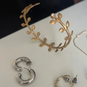 Guldarmband & silverörhängen - Säljer ett stelt guldigt armband med blad, er en par örhängen i silver (chunky mindre hoops). 40kr st eller 60 ihop