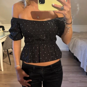 Svart offshoulder topp med prickar - Supersöt svart offshoulder topp med vita prickar och puffiga korta ärmar. Köpt på hm barnavdelning strl 140 men passar mig bra som vanligtvis använder xs/s