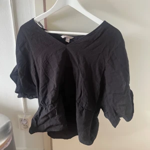 Svart blus med v-ringning - Svart blus/mer uppklädd tshirt från hm. Jätte fin med detalj i midjan som gör den mer formad när man har på sig den. 