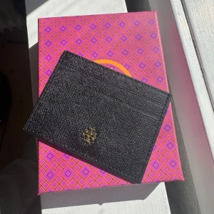Tory Burch korthållare - svart  - Säljer en stilren korthållare från Tory Burch i svart med guldfärgad logga. Den är i princip helt ny – bara öppnad men aldrig använd. Originalbox följer med ✅   Finns att hämta i Jönköping, kan även skickas spårbart! 