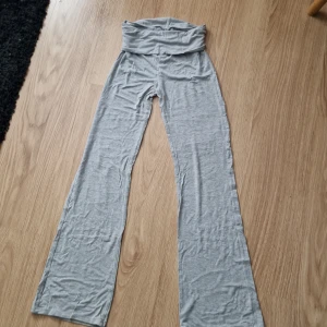 Grå yogabyxor med nerfällbar midja - Superbekväma grå mjukisbyxor med utsvängda ben. Tillverkade i mjukt och stretchigt bomullsmaterial, perfekta för chill eller yoga. Snyggt minimalistiska och lätta att matcha med en hoodie eller crop top.