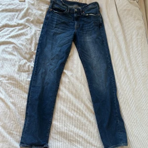 Blå straight jeans från H&M - Snygga blå jeans från H&M i straight regular fit. Klassisk femficksmodell med normal passform och raka ben. Jeansen har en mörkblå tvätt och är tillverkade i bomull. Perfekta för en avslappnad och stilren look.