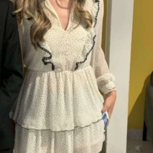 Vit prickig volangklänning från Zara - Supersöt kort klänning från Zara i vitt med svarta prickar. Klänningen har långa ärmar, v-ringning och volangdetaljer framtill samt dubbla volanger i kjolen. Tunn och luftig med markerad midja och svarta kanter på volangerna.💕🌸