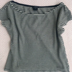 Randig topp från Lindex - Snygg randig topp från Lindex i svart och vitt. T-shirten har korta ärmar och en avslappnad passform. Perfekt till jeans eller kjol för en enkel och stilren look.Går att ha offshulder