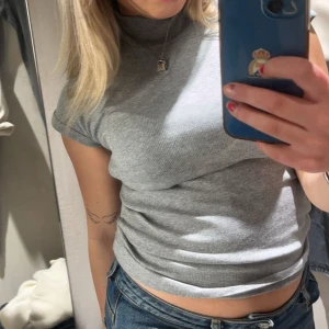 Grå ribbad T-shirt - Trendig grå ribbad T-shirt i superbra skick. Tightare passform med stretchigt material. Använd 1 gång.