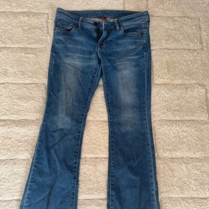 Lågmidjade blå bootcut jeans från Uniqlo - Säljer ett par lågmidjade blå bootcut jeans från Uniqlo. Jeansen har normal passform, fem fickor och subtila slitningar fram, väldigt fina på, knappt andvända 