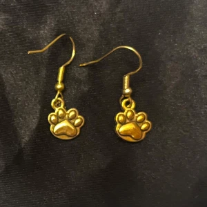 Guldiga tassavtryck örhängen  - Så söta örhängen i form av tassavtryck. Ca  0,7 x 0,6 cm. 