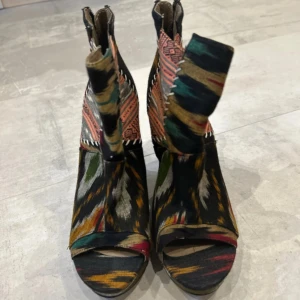 Färgglada kilklackar från ALDO - Unika kilklackar från ALDO med färgstarkt mönster i svart, grön, orange och beige. Skorna har öppen tå, dragkedja bak och plattformsula. Perfekta för dig som vill sticka ut med din stil.💕 Köpte dom i början av 2024 och har använt dom ca 3-4 gånger på olika små fester 🎉   Köpe dom i Kanada för ca 4500kr 🥲 och säljer dom nu för 2500kr!!   Skriv till mig om du har ett bra bud så kan vi snacka om det 💛💛