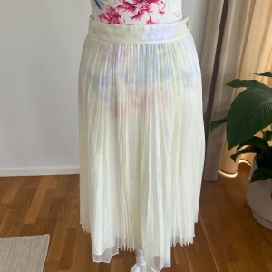 Vit plisserad midikjol med glans Marc by Marc Jacobs  - Säljer en superfin vit plisserad kjol med glansig finish och bred midja. Kjolen har knäppning i sidan och ett skirt, lätt material som ger ett luftigt intryck. Perfekt för dig som gillar en feminin och trendig stil.