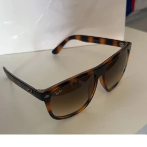 Ray-Ban  solglasögon - Snygga Ray-Ban  solglasögon  med fyrkantig form. Glasen är bruna med snygg toning och bågarna har Ray-Ban-logga på sidan. Perfekta för att lyfta din stil med en tidlös vibe.