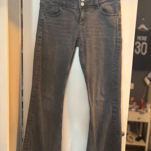 Svarta lågmidjade jeans - Super snygga jeans från Gina Young! Dom har knapp fickor där bak, dom är i bra skick och är i storlek 164 men är uppsydda för att passa storlek 152/158 ungefär