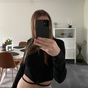 Långärmad croppad tröja - Långärmad croppad tröja med band som man knyter runt magen. Väldigt bra skick och man kan knyta banden på olika sätt. Liten i storlek så den sitter som en m/s. 💕