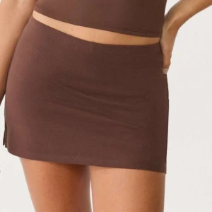 Brun kortkjol i bomull - Enkel och stilren brun kortkjol i mjukt bomullstyg. Kjolen har en tight passform och en liten slits på sidan för extra edge. Perfekt att matcha med crop tops eller oversized tröjor.