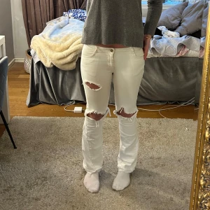 Vita jeans från Claudie Pierlot - Säljer ett par vita jeans från Claudie Pierlot med slitna hål över knäna. Jeansen är lågmidjade och utsydda bootcut! De är i storlek 38🩷