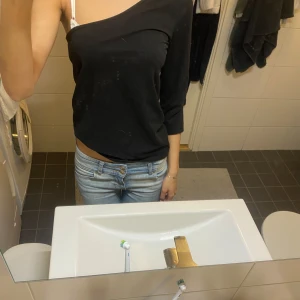 Svart offshoulder topp - Säljer en svart offshoulder topp med trekvartsärm. Snygg och enkel modell som sitter lite löst och visar ena axeln. Perfekt för dig som gillar en stilren och avslappnad look.