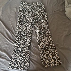 Leopardmönstrade byxor med rak passform - Säljer ett par snygga byxor med leopardmönster i svart och beige. Byxorna har rak passform och normal midja. Perfekta för dig som vill sticka ut lite extra med din stil! Byxorna sitter midwaist/low waist beroende på kroppsform. Fickorna på byxorna är fejk! Dessa byxor är köpta i Chile så dom går ej att hitta någon annanstans! 💌Köparen står för frakten