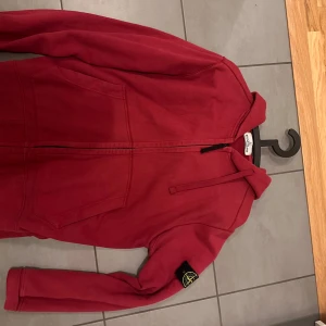 Röd zip-hoodie från Stone Island - Röd hoodiejacka från Stone Island. Sparsamt använt. Inte använt på flera år. 