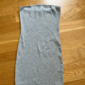 Grå ribbad klänning  - Säljer en enkel och stilren grå ribbad klänning . Perfekt att matcha med jeans eller kjol för en clean look. Mjuk och stretchig i materialet. Ny 