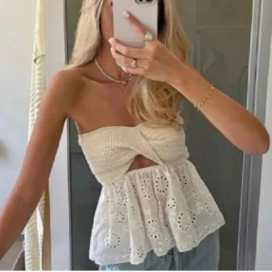 Vit axelbandslös topp med broderade detaljer - Säljer en söt axelbandslös topp i vitt med twistad byst och broderade. Perfekt till sommaren och passar till jeans eller kjol💕