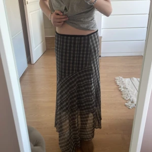 Svart och vit rutig långkjol - Säljer en svart och vit långkjol med rutigt mönster. Kjolen har en asymmetrisk skärning och är i ett lätt, genomskinligt material.💞 Den har en innerkjol också💞